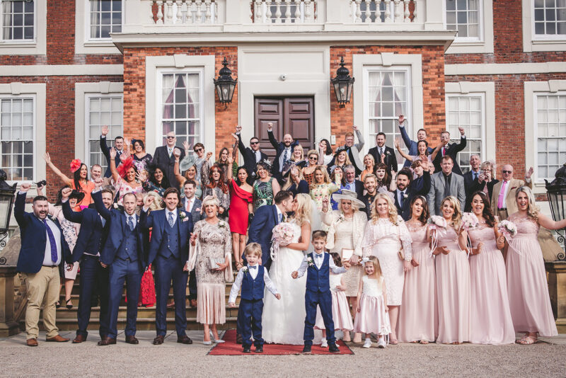 Wedding guests standing outside Knowsley Hall for wedding photographs