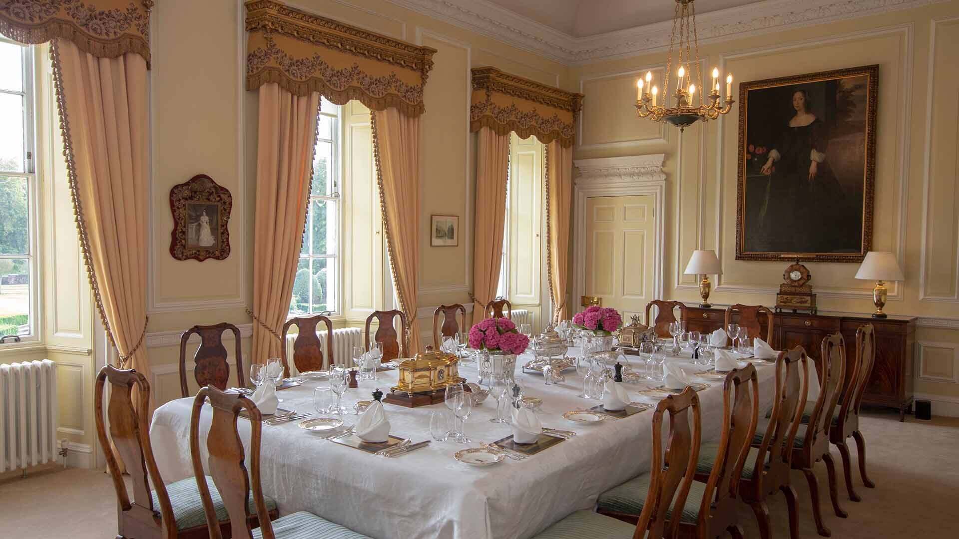 Private dining room with long dining table with chairs dressed for an elegant lunch with beautiful pink flowers