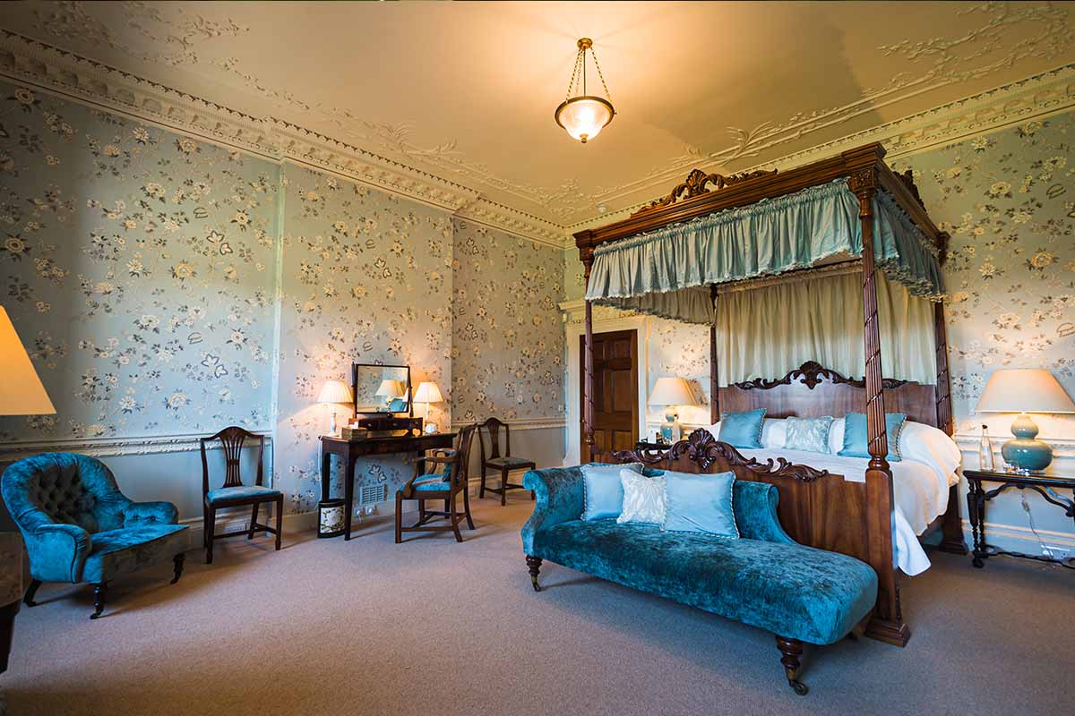 Spacious bedroms with four poster mahogany bed. Chaise longe in blue velvet fabric.