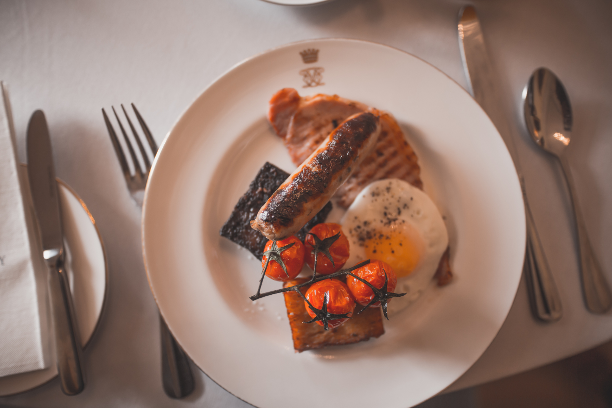 Full English Cooked breakfast of sausage, bacon, egg, tomatoes an hash browns