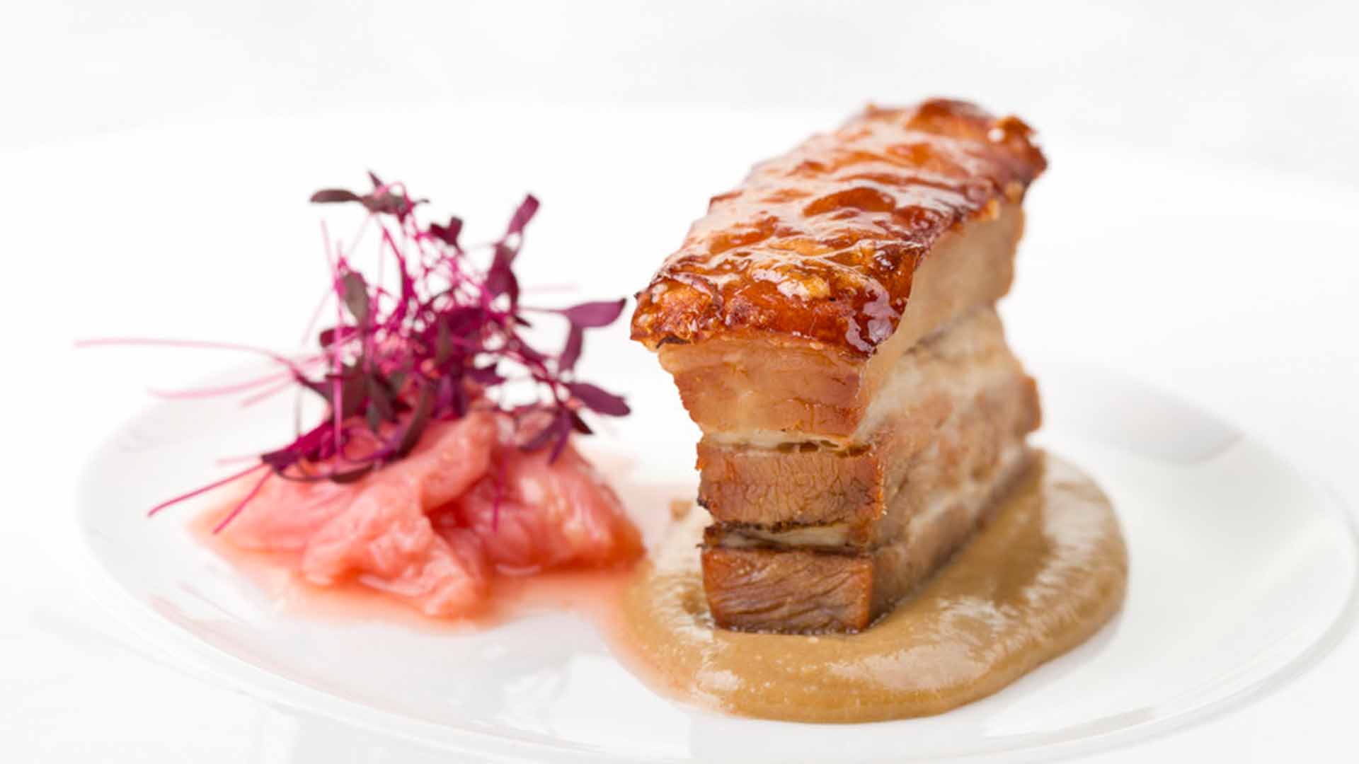 A food picture of a piece of pork with crackling on a plate