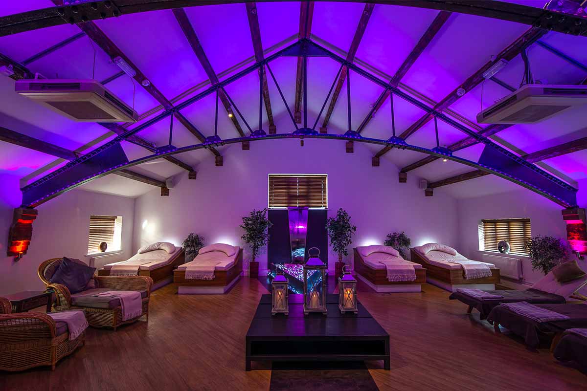 A relaxation room with ambient lighting and beds to relax on during spa day