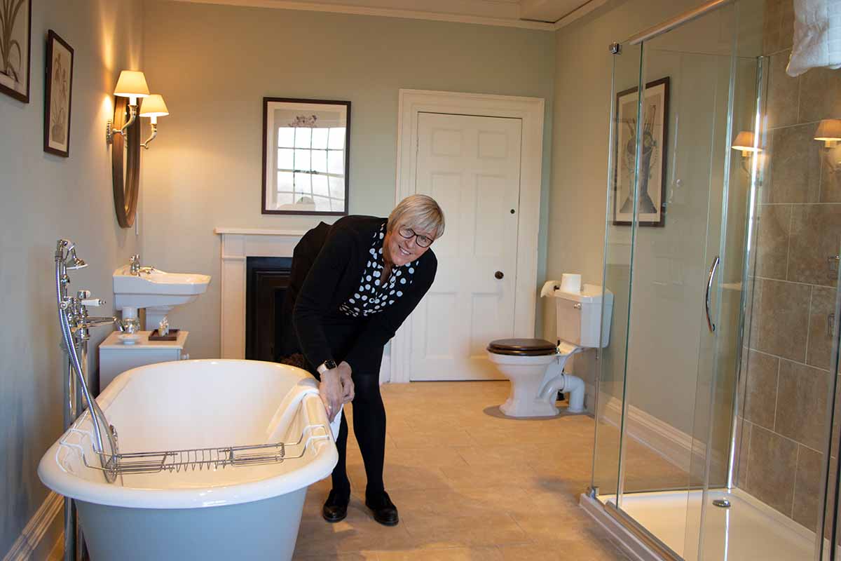 Housekeeper folding towel in bathroom at Knowsley Hall