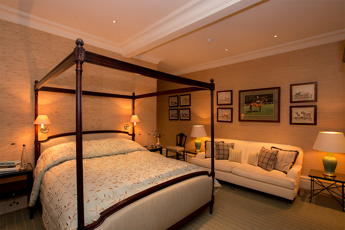 Luxury bedroom with four poster bed and sofa in Knowsley Hall, a stately home in Merseyside